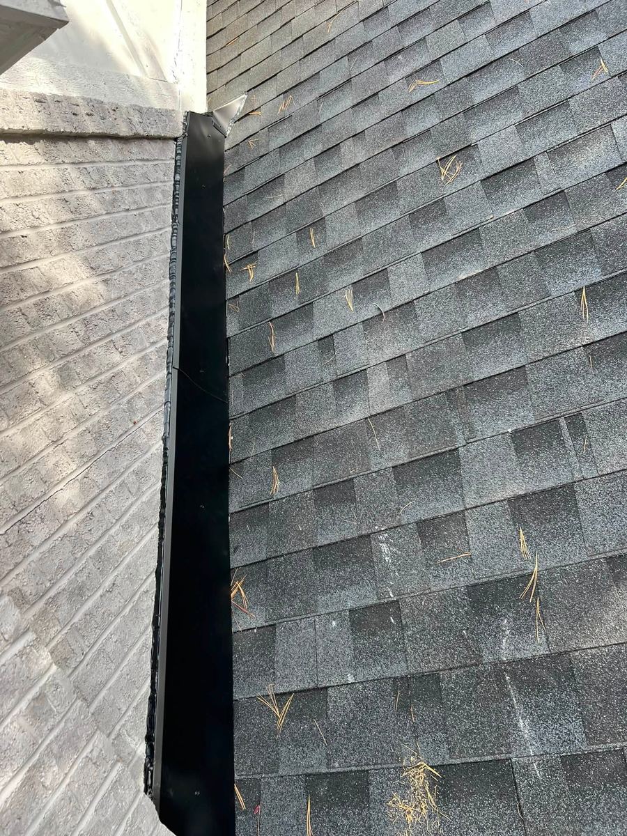 New shingles meeting a brick chimney with new metal flashing