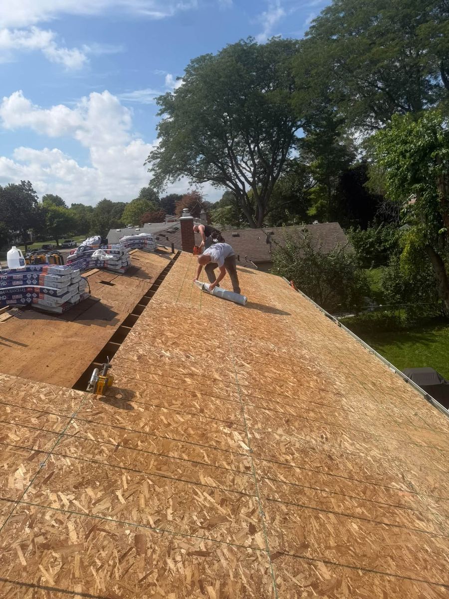 A DripRite roofer laying fresh OSB decking across a stripped roof