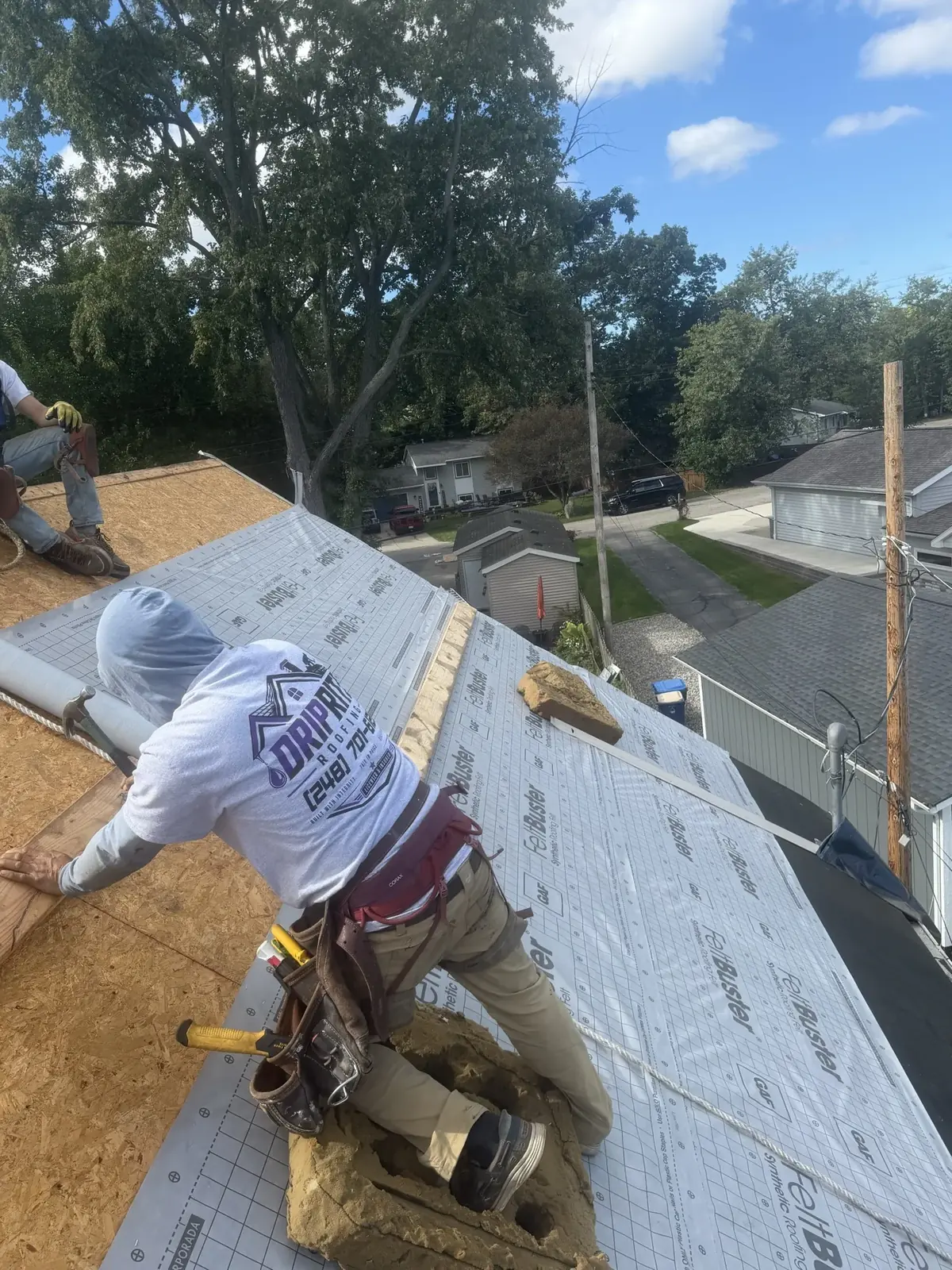 A DripRite crew member in a DripRite shirt installing synthetic underlayment over new roof decking